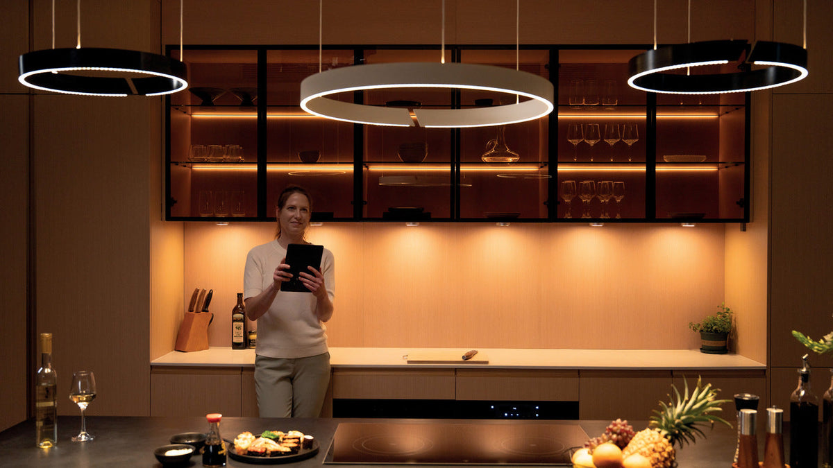 Kitchen with illuminated wall cabinets, warm under-cabinet lighting and ring pendant lights.